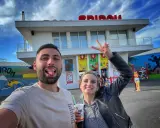 Un couple s'amuse devant le parc Spirou. La femme fait un signe de paix. Combien de temps pour faire le parc Spirou ? Une journée entière !
