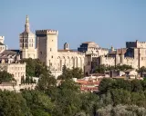 Vue panoramique de la cité des papes, avec le Palais des Papes imposant et ses tours crénelées, baignée de soleil.