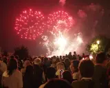Foule admirant un magnifique feu d'artifice rouge au-dessus de la nuit, un spectacle mémorable à Lourmarin.