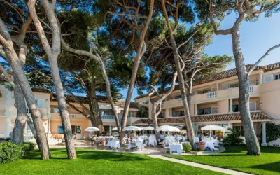 Un magnifique cheval blanc se promène dans un jardin luxuriant en Provence, près d'un hôtel de luxe avec terrasse.