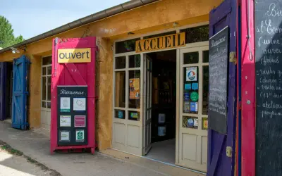 L'entrée colorée du musée des ocres, avec un panneau "Ouvert" et des affiches "Bienvenue".