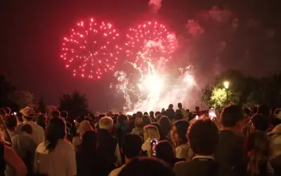 Foule admirant un magnifique feu d'artifice rouge au-dessus de la nuit, un spectacle mémorable à Lourmarin.