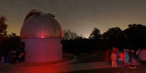 Nuit étoilée au saint michel l'observatoire. Un dôme d'observation et un groupe d'astronomes observent le ciel.
