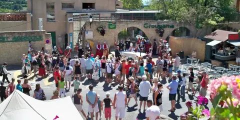 Foule en costume d'époque lors de la fête de la veraison, avec des musiciens et des stands.
