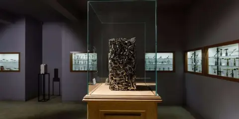 Sculpture en tire-bouchons dans une vitrine au musée du tire bouchon. Des vitrines murales exposent d'autres tire-bouchons anciens.