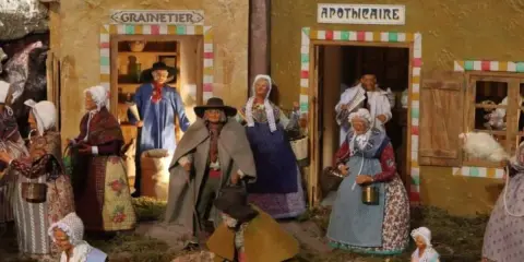 Scène de village provençal avec santons. Découvrez les plus belles crèches de Noël en Provence, avec des personnages costumés devant le grainetier et l'apothicaire.