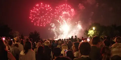 Foule admirant un magnifique feu d'artifice rouge au-dessus de la nuit, un spectacle mémorable à Lourmarin.