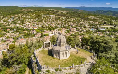 Vue aérienne de la citadelle de Forcalquier, avec son dôme imposant et le village pittoresque en arrière-plan.