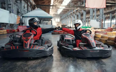 Deux pilotes en karts se donnent un fist bump, prêts pour une course de karting Vaucluse.