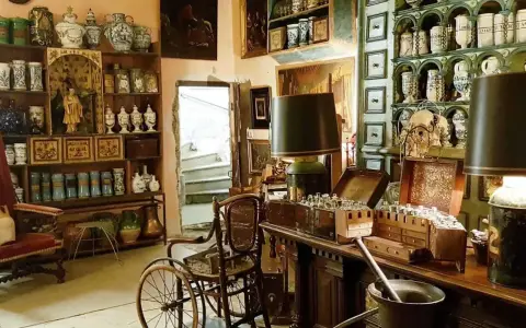 Intérieur d'un **hôtel d'Agar** rempli d'antiquités, de pots en céramique, de meubles anciens et d'une chaise à porteurs.