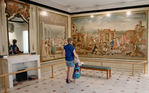 Une mère et sa fille admirent une fresque historique lors d'une exposition dans le Vaucluse.