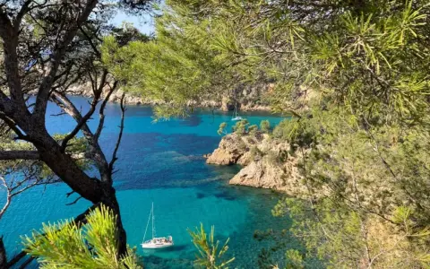 Vue sur la côte rocheuse et la mer turquoise de Bandol, avec des voiliers. Idéal pour savoir que faire à Bandol.