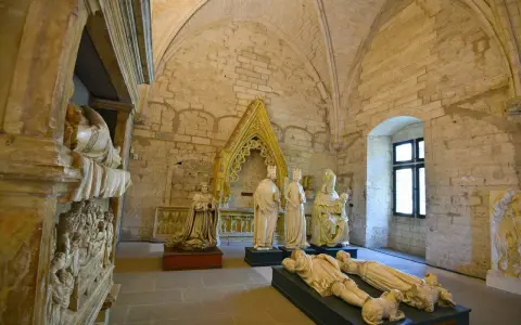 Intérieur du Palais des Papes à Avignon : gisants, statues royales et religieuses sous des voûtes de pierre.