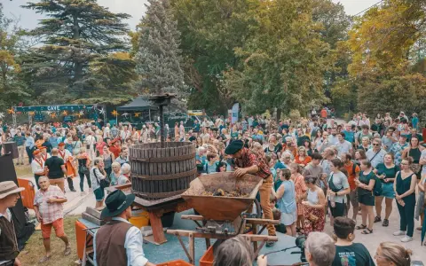 Foule joyeuse à Avignon pour le ban des vendanges, avec un pressoir à vin traditionnel au centre.