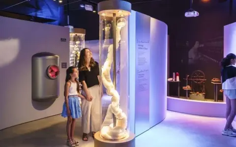 Une mère et sa fille découvrent la filaventure dans un musée interactif, fascinées par une colonne de fibres.