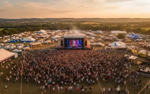 Scène de concert animée lors du festival Monteux, avec une foule immense sous un ciel doré.