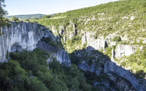 Vue plongeante sur les gorges d'Oppedette, falaises calcaires abruptes couvertes de végétation luxuriante sous un ciel bleu.