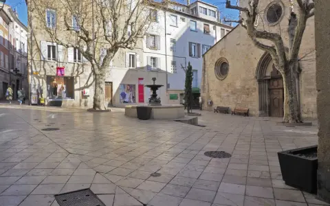 Place de l'église Saint-Sauveur à Manosque, avec sa fontaine et ses platanes dénudés.