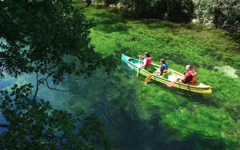 Trois personnes en canoë sur la Durance, profitant d'une baignade rafraîchissante dans des eaux turquoise et verdoyantes.