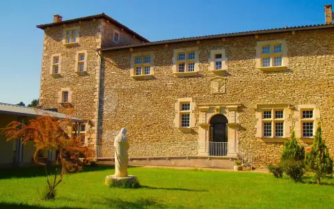 Statue de la Vierge devant la façade en pierre de la blauvac abbaye, sous un ciel bleu éclatant.
