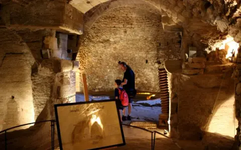Un homme et un enfant explorent les caves du palais saint-firmin, un lieu historique aux voûtes de pierre.