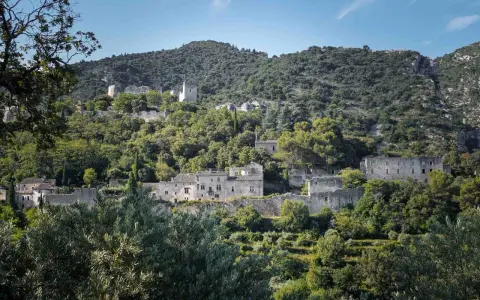 Vestiges de l'oppidum le Vieux, un village perché sur une colline verdoyante, baigné de soleil.