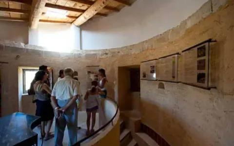 Visite du moulin de Salignan, un groupe découvre les panneaux d'exposition dans l'espace circulaire aux murs de pierre.