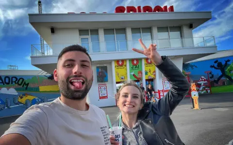 Un couple s'amuse devant le parc Spirou. La femme fait un signe de paix. Combien de temps pour faire le parc Spirou ? Une journée entière !