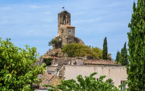 La tour de l'église de Lourmarin, perchée sur une colline rocheuse, domine le village. Un cadran solaire orne son flanc.