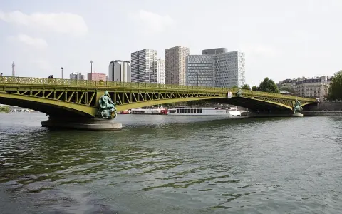 Le pont Mirabeau, avec ses statues de sirènes, enjambe la Seine, bordée par des immeubles modernes et des péniches.