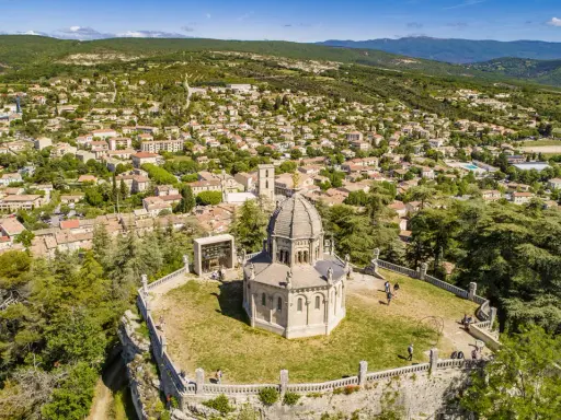 Vue aérienne de la citadelle de Forcalquier, avec son dôme imposant et le village pittoresque en arrière-plan.