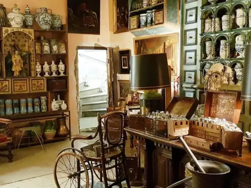 Intérieur d'un **hôtel d'Agar** rempli d'antiquités, de pots en céramique, de meubles anciens et d'une chaise à porteurs.