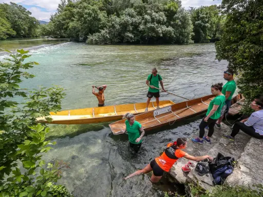 Des gens préparent des barques en bois pour une balade sur la Sorgue, un moment de partage des eaux à L'Isle-sur-la-Sorgue.