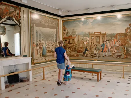 Une mère et sa fille admirent une fresque historique lors d'une exposition dans le Vaucluse.