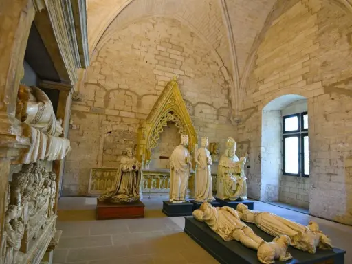 Intérieur du Palais des Papes à Avignon : gisants, statues royales et religieuses sous des voûtes de pierre.