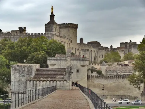 Le Palais des Papes, un incontournable pour tout guide Avignon, se dresse majestueusement. Des touristes explorent ce site historique.