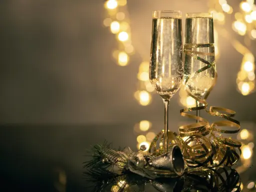 Deux flûtes de champagne pétillant, décorées de rubans dorés, prêtes pour le nouvel an à Avignon. Lumières festives en arrière-plan.