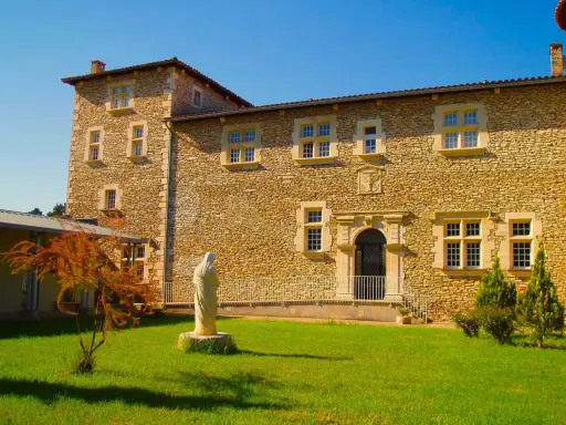 Statue de la Vierge devant la façade en pierre de la blauvac abbaye, sous un ciel bleu éclatant.
