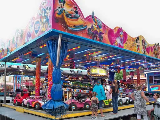 Attraction for children with cars, decorated with Mickey Mouse and friends. A sign says "Paris Dakar".