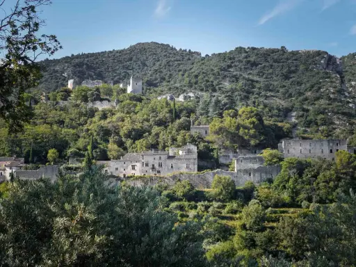 Vestiges de l'oppidum le Vieux, un village perché sur une colline verdoyante, baigné de soleil.