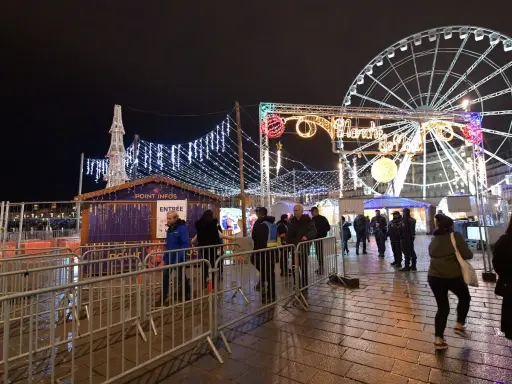 Un marché de Noël illuminé à Vaucluse, avec une grande roue et des chalets festifs.