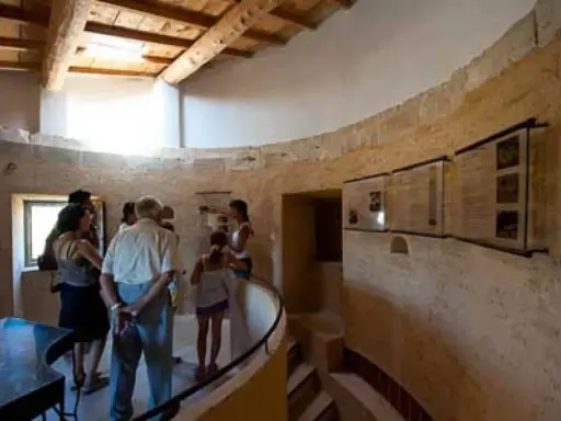 Visite du moulin de Salignan, un groupe découvre les panneaux d'exposition dans l'espace circulaire aux murs de pierre.