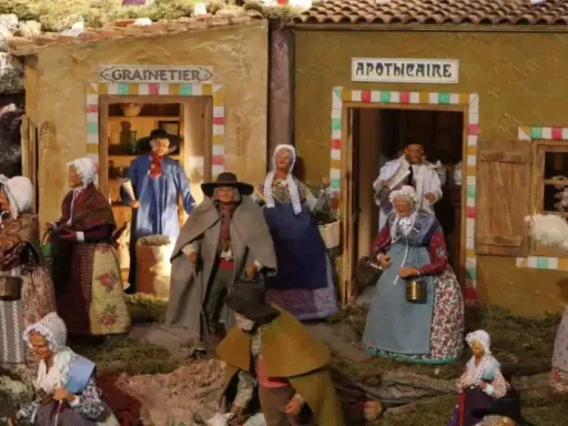 Scène de village provençal avec santons. Découvrez les plus belles crèches de Noël en Provence, avec des personnages costumés devant le grainetier et l'apothicaire.