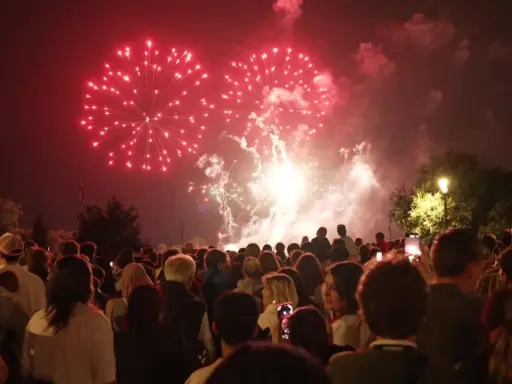 Foule admirant un magnifique feu d'artifice rouge au-dessus de la nuit, un spectacle mémorable à Lourmarin.