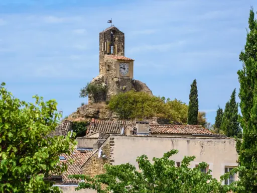 La tour de l'église de Lourmarin, perchée sur une colline rocheuse, domine le village. Un cadran solaire orne son flanc.
