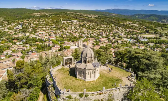 Vue aérienne de la citadelle de Forcalquier, avec son dôme imposant et le village pittoresque en arrière-plan.