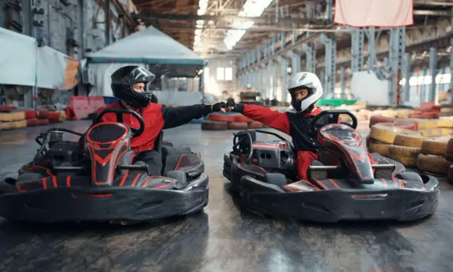 Deux pilotes en karts se donnent un fist bump, prêts pour une course de karting Vaucluse.