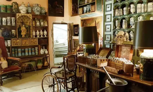 Intérieur d'un **hôtel d'Agar** rempli d'antiquités, de pots en céramique, de meubles anciens et d'une chaise à porteurs.