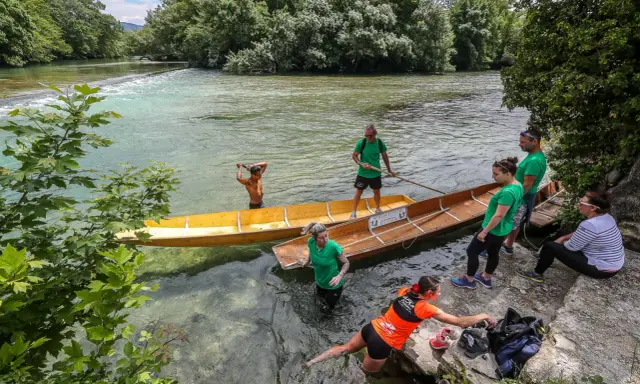 Des gens préparent des barques en bois pour une balade sur la Sorgue, un moment de partage des eaux à L'Isle-sur-la-Sorgue.