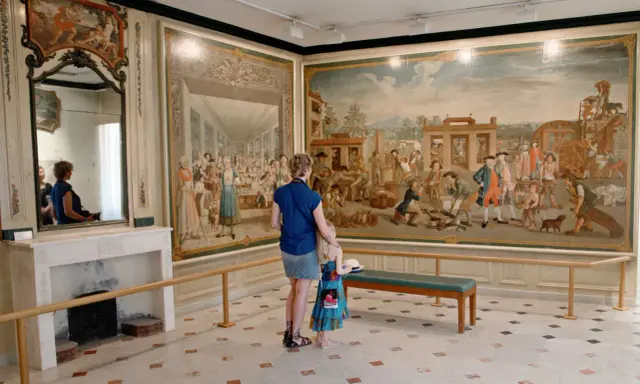 Une mère et sa fille admirent une fresque historique lors d'une exposition dans le Vaucluse.